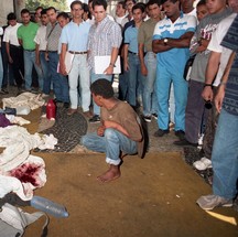 Sobrevivente observa as roupas sujas de sangue. Crime foi motivado pelo apedrejamento de um carro da PM na véspera — Foto: Ricardo Leoni / Agência O Globo