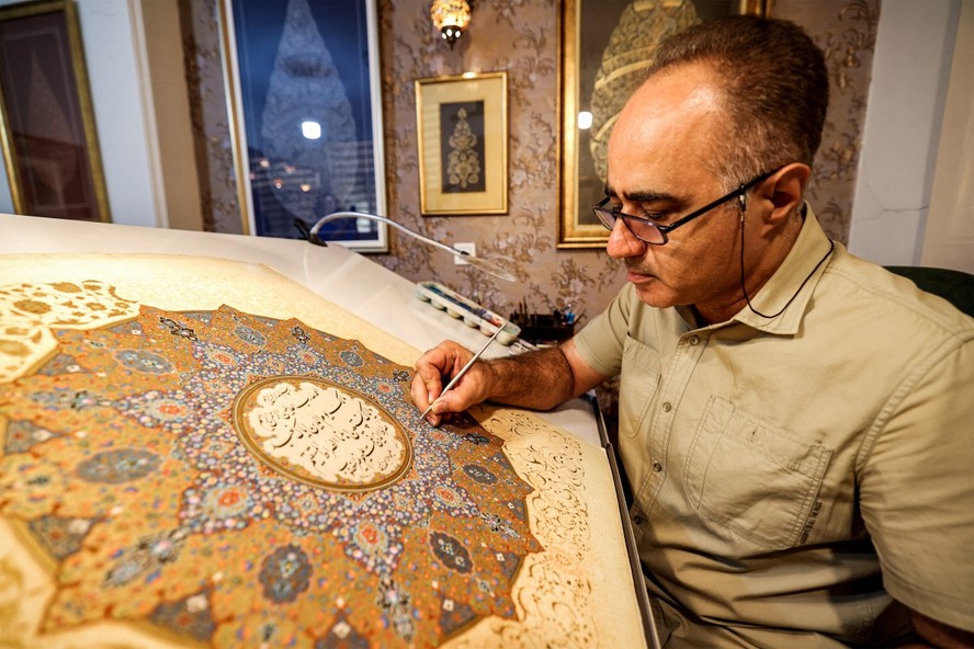 Mohammad Hossein Aghamiri, artista especializado em miniaturas persas, trabalha em uma de suas peças que retrata al-Fatiha
