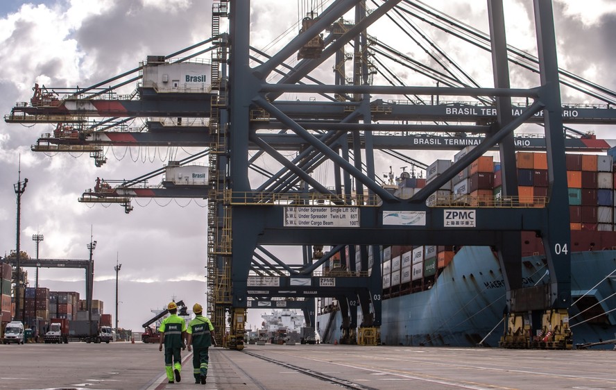 Trabalhadores ao lado de um navio atracado no Porto de Santos, no literal de São Paulo, no terminal de exportação da  BTP