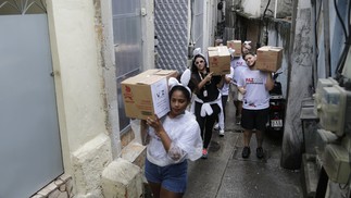 Voluntários carregam caixas de chocolates pelas vielas das comunidades