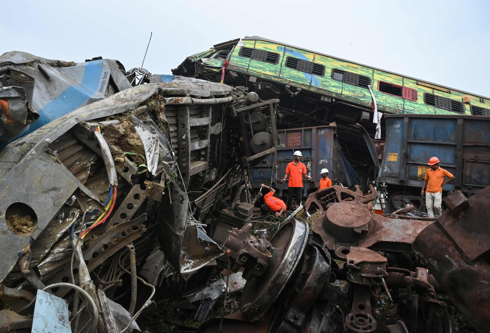 Equipes de resgate se reúnem em torno dos trens danificados no local da colisão perto de Balasore, a cerca de 200 km da capital do estado Bhubaneswar — Foto: Dibyangshu SARKAR / AFP)