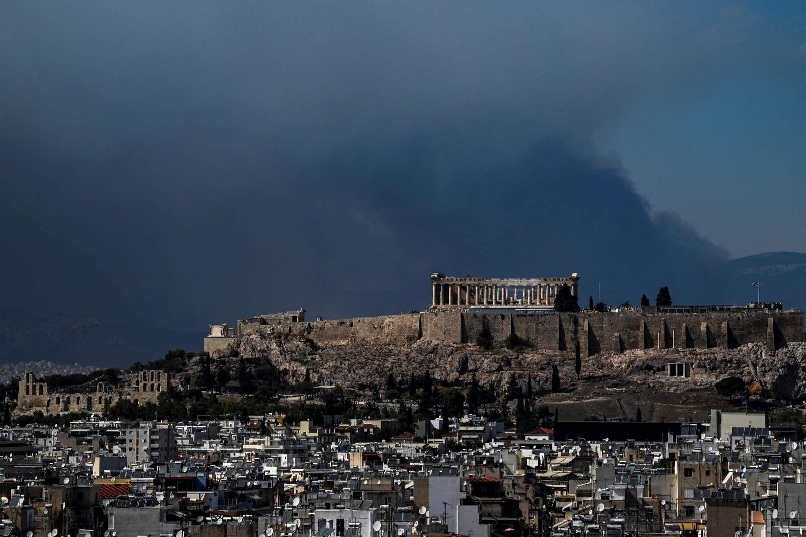 A fumaça sobe atrás do antigo templo do Parthenon no topo da colina da Acrópole enquanto um incêndio florestal se espalha nos arredores de Atenas — Foto: Aris MESSINIS / AFP