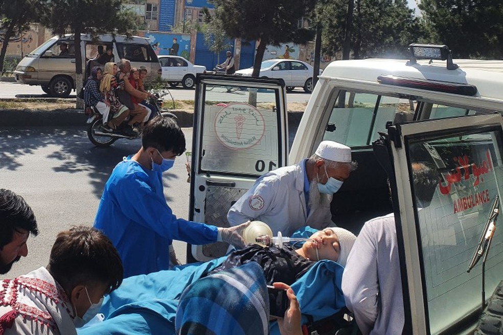 Médicos e parentes acompanham vítima de ataque contra escola no Afeganistão — Foto: AFP