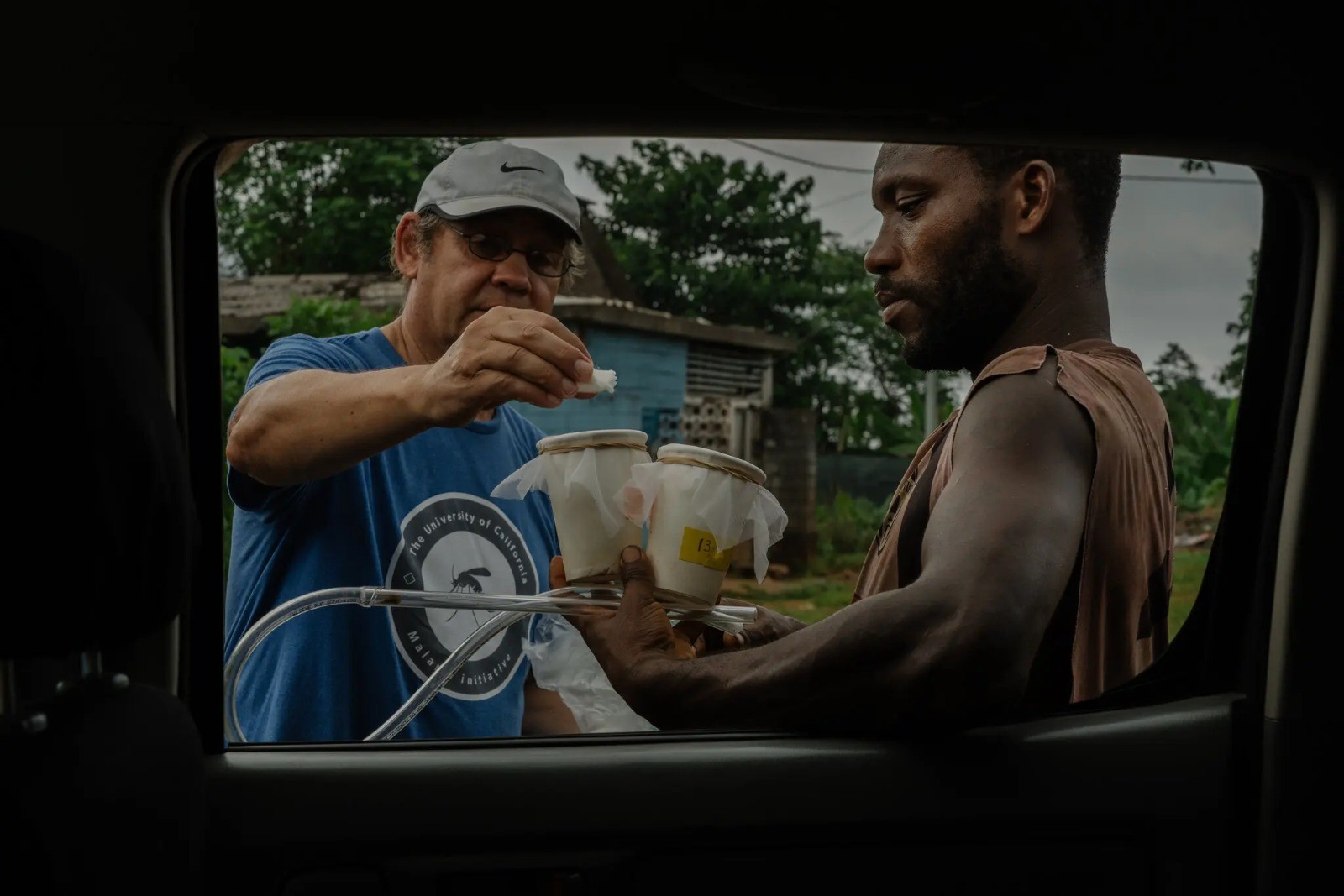 Anton Cornel, à esquerda, explica os passos para uma coleta noturna de mosquitos para um coletor voluntário na vila de São Joaquim — Foto: Natalija Gormalova / The New York Times