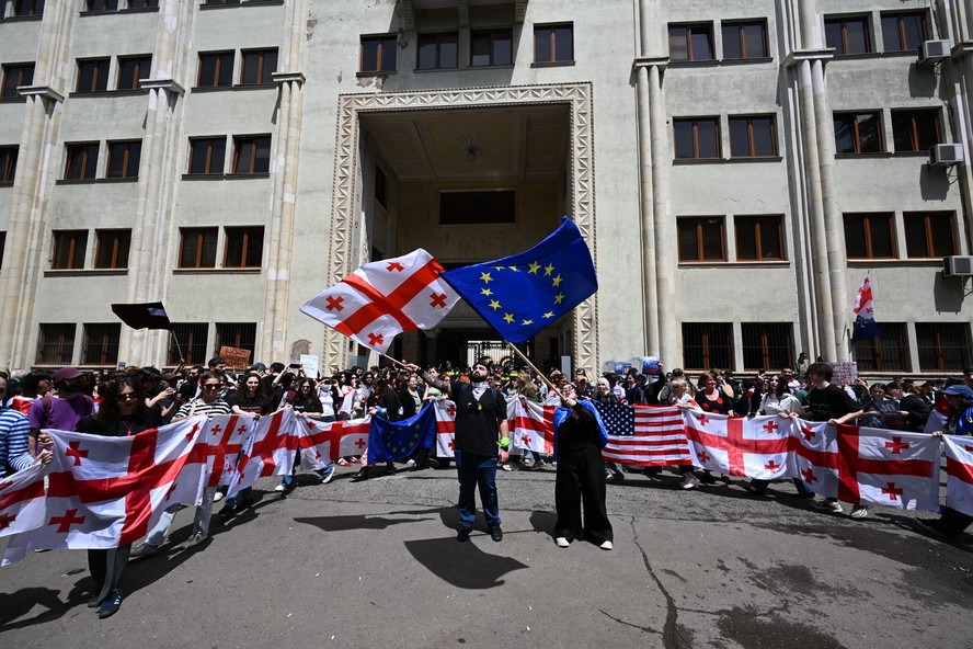 Manifestantes protestando contra a lei de 'influência estrangeira' se aglomeram em frente ao prédio do Parlamento no centro de Tbilisi, capital da Geórgia