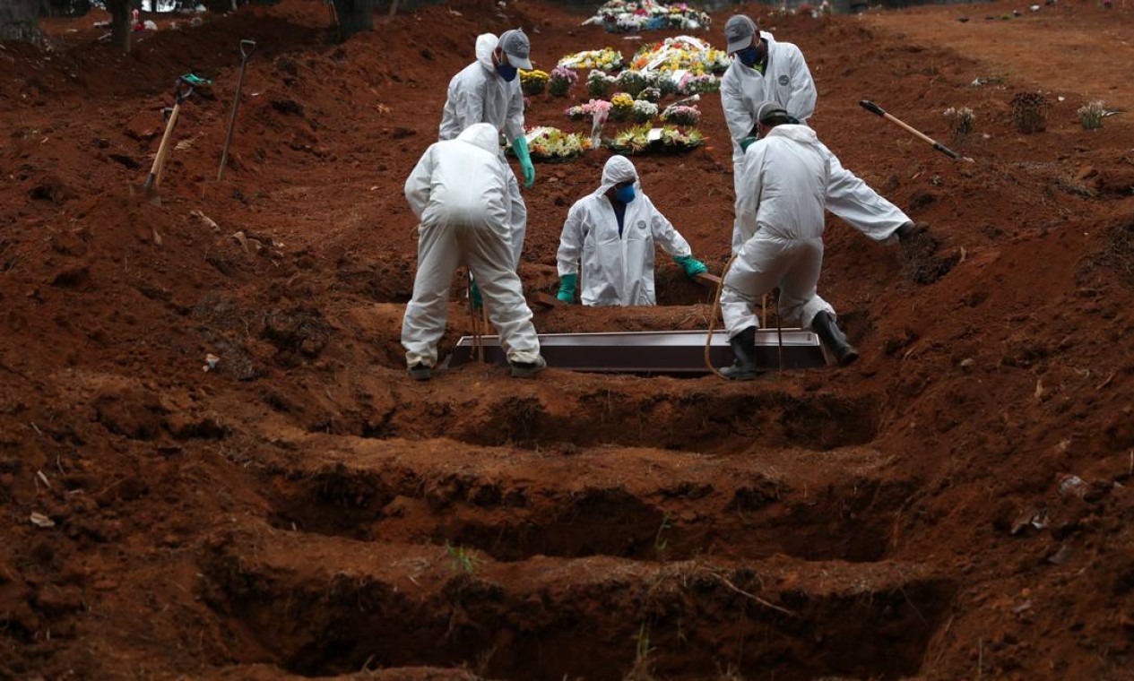 Coveiros vestindo roupas de proteção enterram o caixão de uma vítima da COVID-19, no cemitério São Luiz, em São Paulo — Foto: AMANDA PEROBELLI / Reuters
