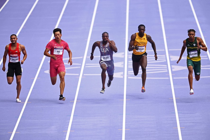 O americano Noah Lyles (ao centro), durante as eliminatórias dos 100m, no Stade de France