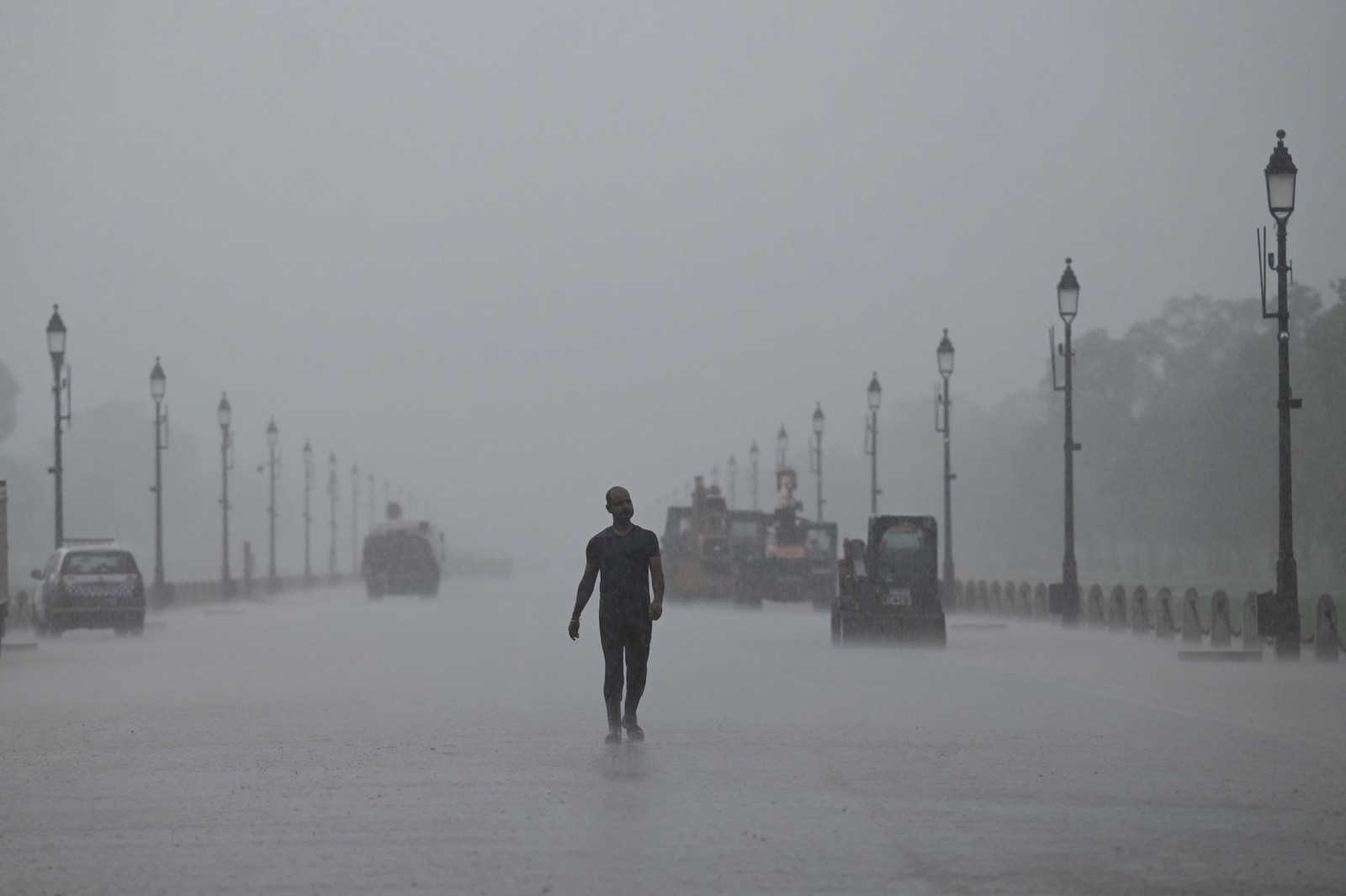 Homem caminha ao longo de Rajpath durante uma chuva de monção em Nova Délhi, Índia  — Foto: MONEY SHARMA / AFP