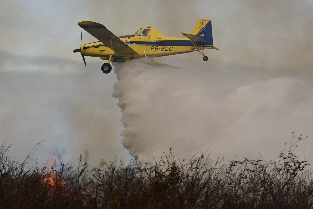 Avião do ICMBio despeja água sobre área em chamas no Pantanal — Foto: Pablo PORCIUNCULA / AFP
