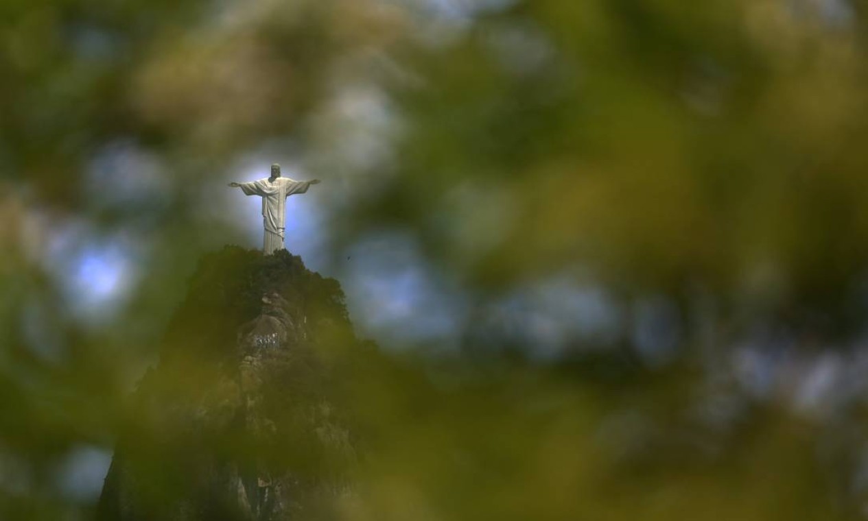 Estátua do Cristo é vista entre folhagem de árvore  — Foto: Custódio Coimbra / Agência O Globo