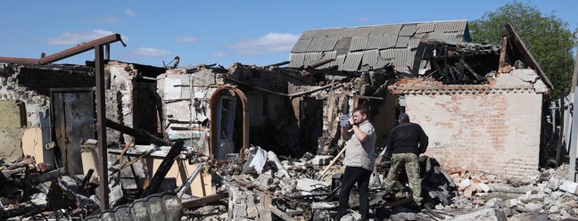 Moradores locais examinam uma casa particular destruída por um ataque de mísseis na vila de Krasylivka, região de Kiev, em 8 de maio de 2024, em meio à invasão russa na Ucrânia. — Foto: Anatolii STEPANOV/AFP