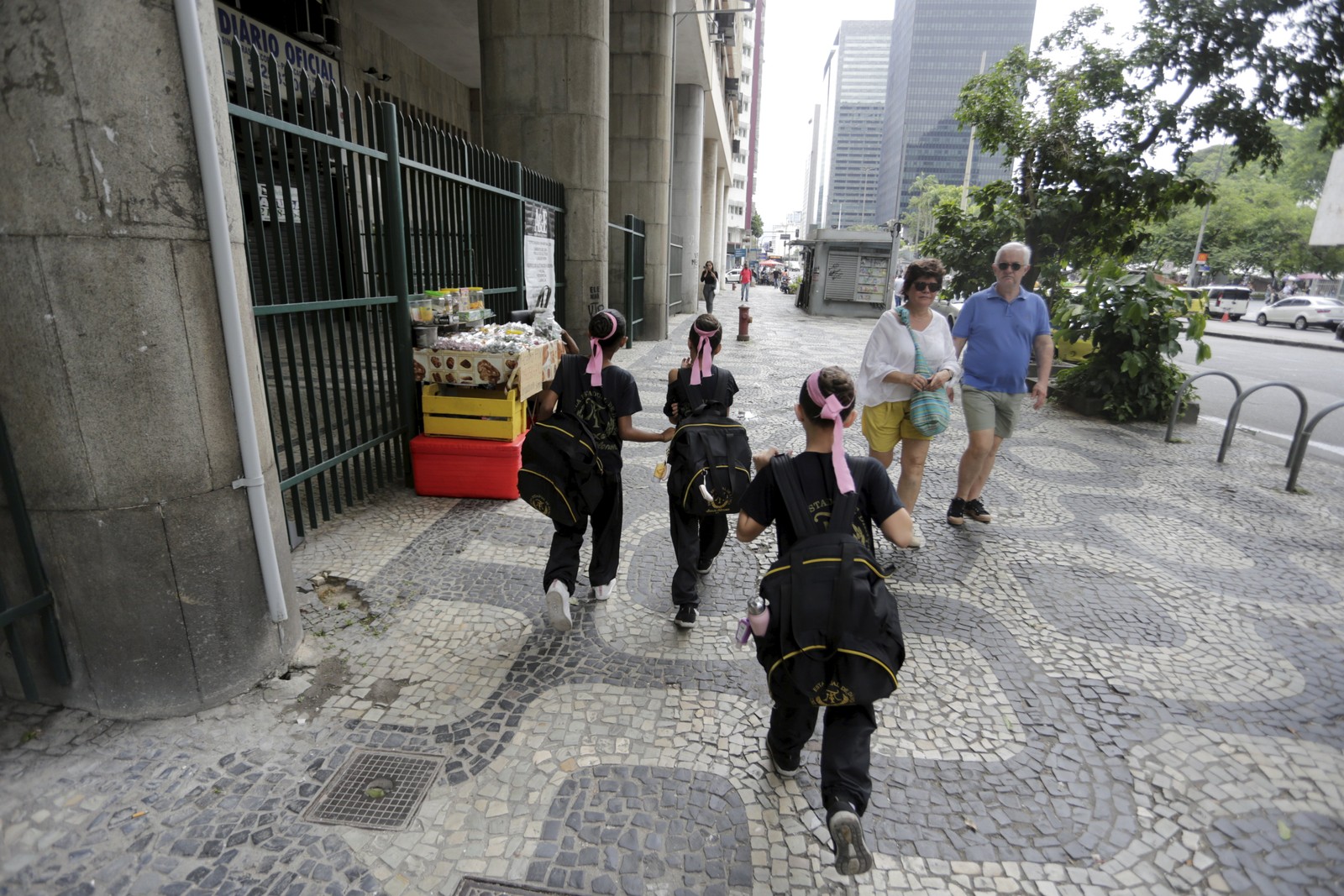 Correria. Meninas andam com pressa em direção à entrada lateral do Theatro Municipal