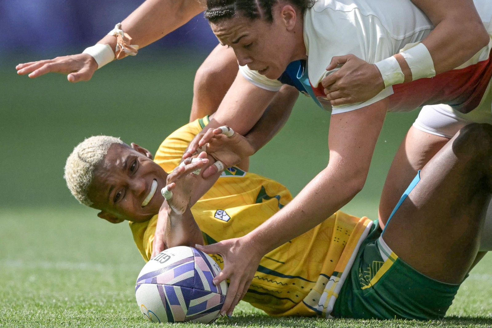 A brasileira Yasmim Soares e a francesa Carla Neisen lutam pela bola durante a partida de rúgbi de sete — Foto: CARL DE SOUZA/AFP