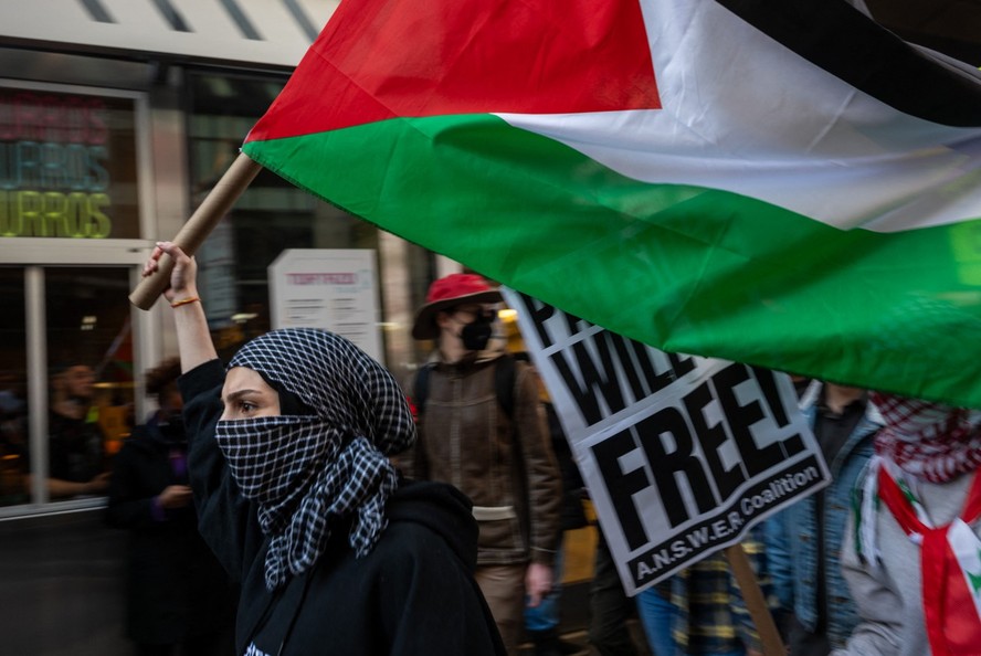 Manifestante levanta bandeira da Palestina em protesto em defesa à população em Nova York, nos EUA