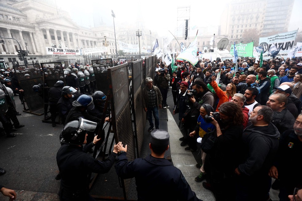 Polícia cria barreira em frente a manifestantes em frente ao Congresso argentino durante votação da Lei de Bases — Foto: Tomas Cuesta/AFP