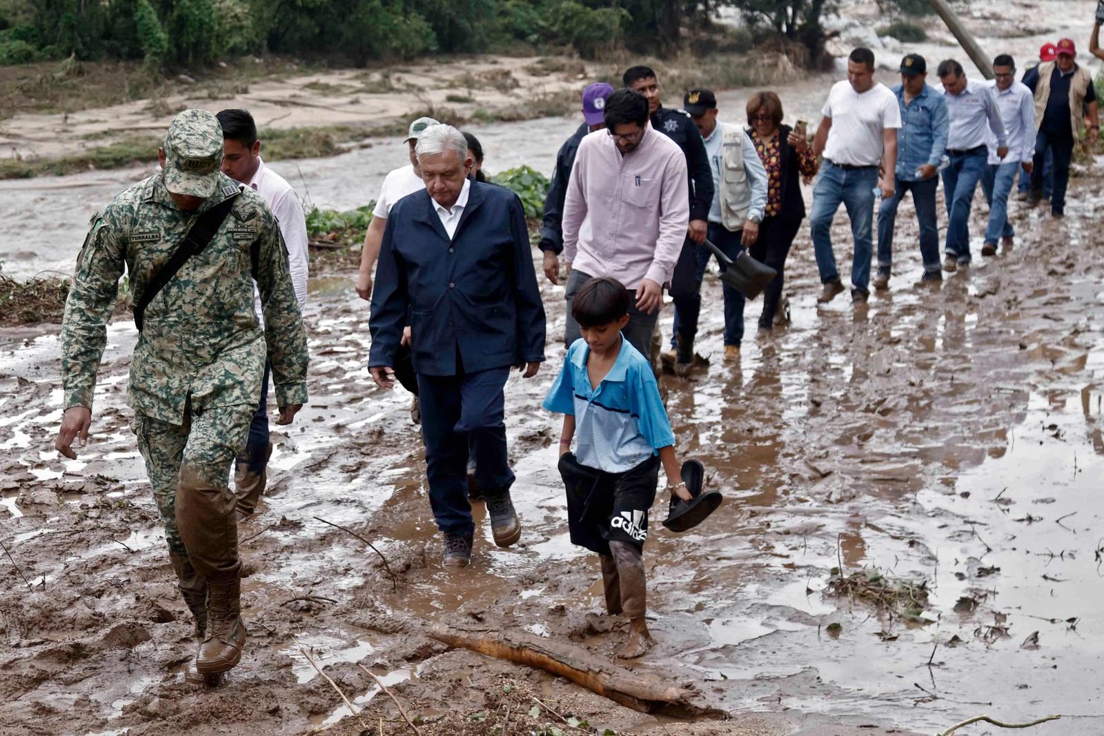 O presidente mexicano Andres Manuel Lopez Obrador e membros de seu gabinete caminham na lama enquanto visitam a comunidade El Kilometro 42, perto de Acapulco, estado de Guerrero, México — Foto: RODRIGO OROPEZA/AFP