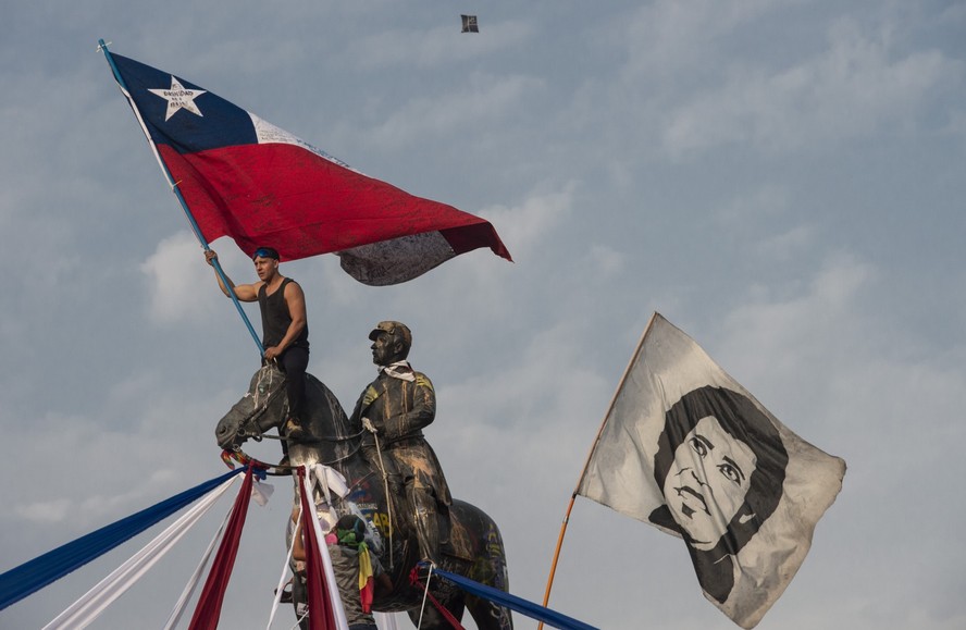 Um manifestante agita uma bandeira nacional chilena ao lado de outra bandeira representando o músico chileno Victor Jara durante um protesto contra o governo do presidente Piñera, em Santiago, em 17 de janeiro de 2020