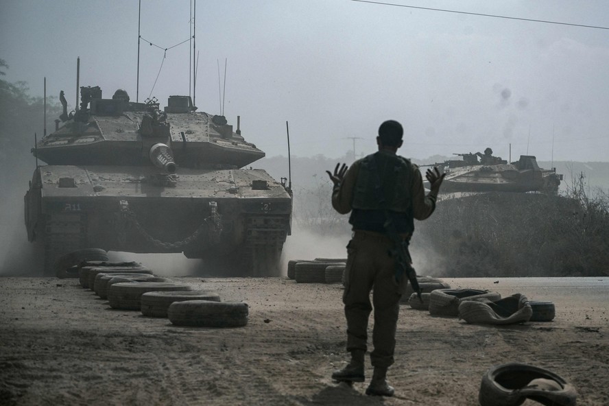 Soldado israelense orienta tanque de guerra Merkava enquanto outro se posiciona ao longo da fronteira com a Faixa de Gaza, no sul de Israel