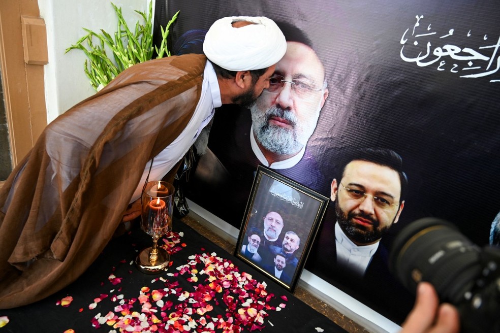 Homem beija um retrato do presidente Ebrahim Raisi durante uma cerimônia fúnebre realizada no Centro Cultural Iraniano em Pexauar, cidade no Paquistão. — Foto: ABDUL MAJEED/AFP