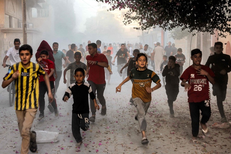 Crianças palestinas correm enquanto fogem do bombardeio israelense em Rafah, no sul da Faixa de Gaza