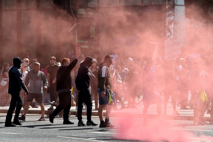 Manifestantes lançam sinalizadores em direção aos policiais em Liverpool durante a manifestação 'Enough is Enough'