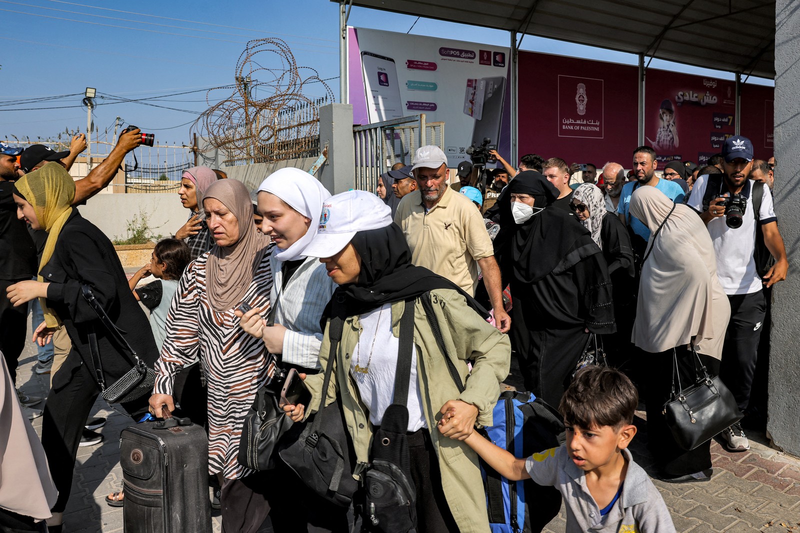 Pessoas atravessam um portão para entrar na passagem de fronteira de Rafah para o Egito, no sul da Faixa de Gaza — Foto: Mohammed ABED/AFP