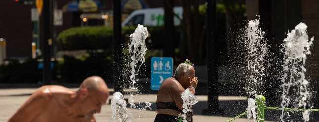 Pessoas se refrescam em uma fonte perto do rio Hudson durante uma onda de calor  na cidade de Nova York. O calor mortal que cobriu recentemente os EUA, o México e a América Central tornou-se 35 vezes mais provável devido ao aquecimento global, disseram cientistas climáticos da World Weather Attribution (WWA) em 20 de junho. — Foto: Yuki IWAMURA / AFP