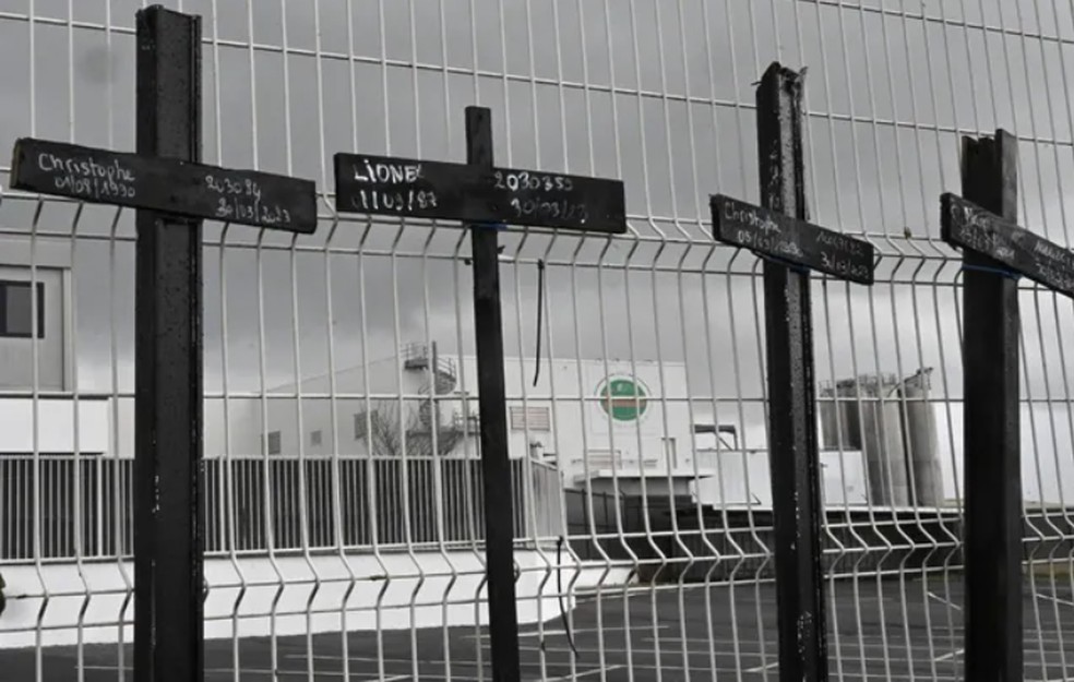 Cruzes são penduradas nas grades da empresa Buitoni após fechamento do local pela Nestlé — Foto: AFP