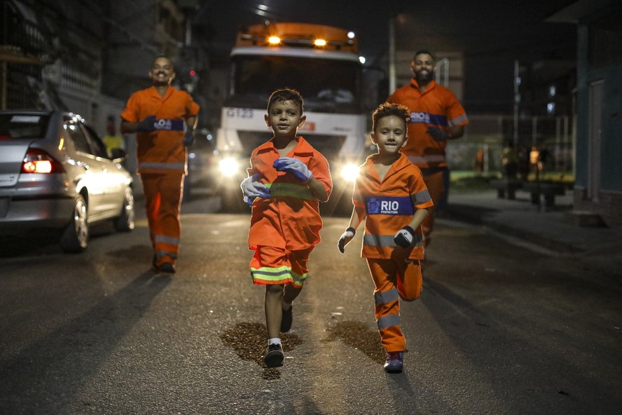 Os irmãos Bryan, de 6 anos, e Bernardo, de 7, ajudam garis a recolher materiais recicláveis