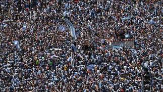 Torcedores da Argentina esperam o ônibus com os jogadores da Argentina para passar pelo Obelisco para comemorar após vencer a Copa do Mundo do Catar 2022 em Buenos Aires — Foto: Luis ROBAYO / AFP