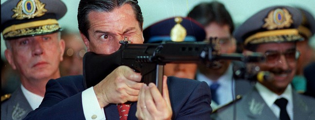 O presidente Fernando Collor durante cerimônia militar aponta um fuzil do Exército, em 1990 — Foto: Marcelo Carnaval / Agência O Globo