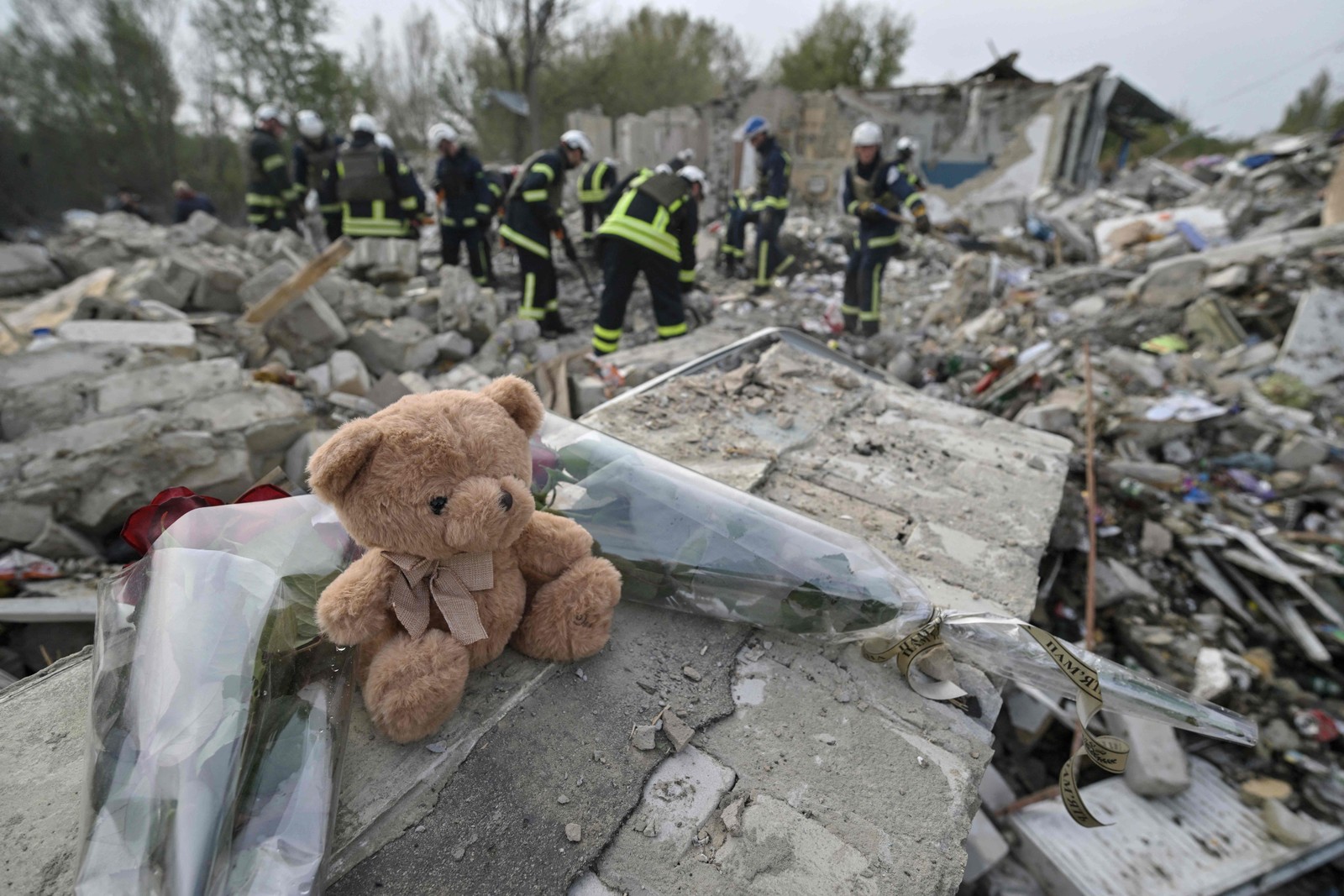 Um ursinho de pelúcia e flores são exibidos no fragmento de uma parede onde uma criança foi retirada sem vida dos escombros na vila de Groza, cerca de 30 quilômetros a oeste de Kupiansk — Foto: Genya SAVILOV / AFP