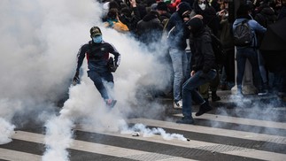 Manifestante chuta uma bomba de gás lacrimogêneo durante confrontos com a polícia na Praça da Bastilha, em Paris — Foto: Christophe ARCHAMBAULT / AFP