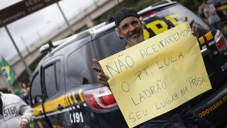 Antidemocrático. Manifestante exibe cartaz contra o resultado das urnas ao lado de viatura da Polícia Rodoviária Federal, na Rodovia Helio Smidt (SP-019) — Foto: Maria Isabel Oiveira/Agência O Globo