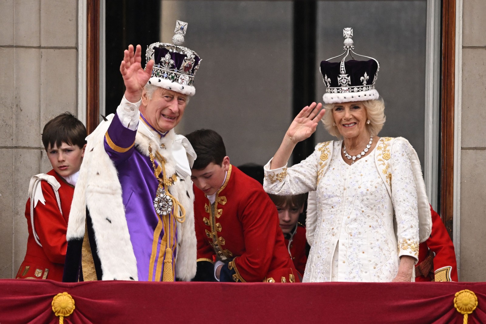 Charles III, vestindo a Coroa do Estado Imperial, e a rainha Camilla, com uma versão modificada da Coroa da Rainha Maria, acenam para os súdito da varanda do Palácio de Buckingham  — Foto: Oli SCARFF / AFP