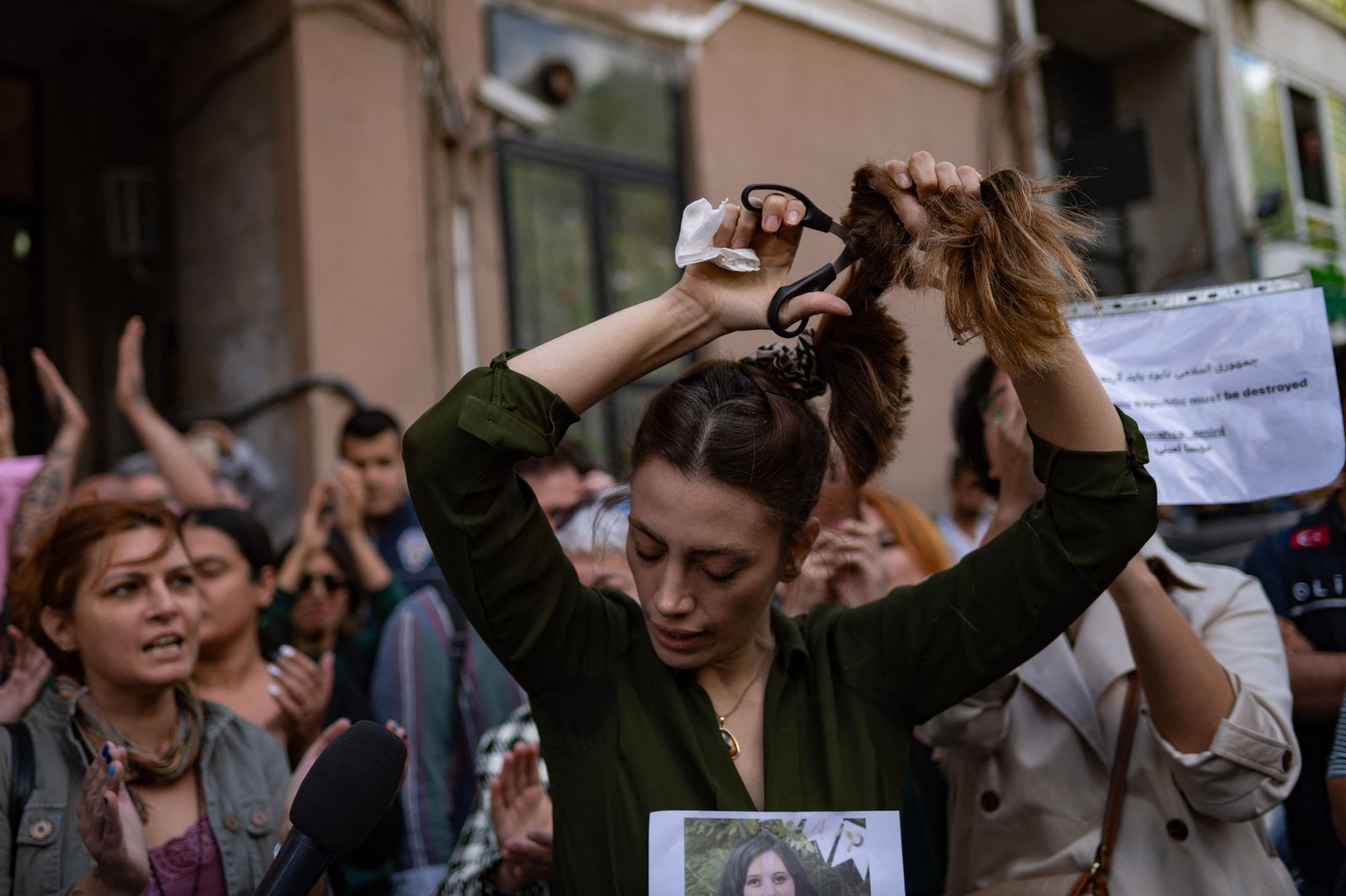 Nasibe Samsaei, iraniana que vive na Turquia, corta seu rabo de cavalo durante um protesto em frente ao consulado iraniano em Istambul — Foto: Yasin AKGUL / AFP