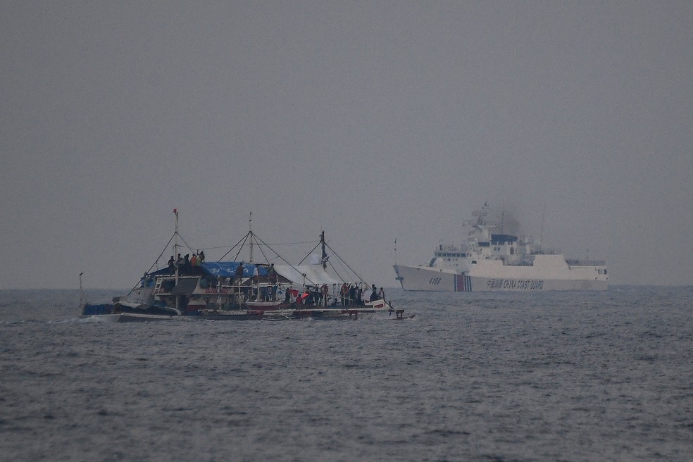 Navio da Guarda Costeira da China pass perto de barco de pesca filipino — Foto: Ted Aljibe/AFP
