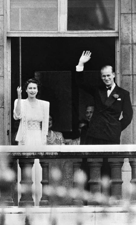 A princesa Elizabeth II e o príncipe Philip, duque de Edimburgo, acenam para a multidão da varanda do Palácio de Buckingham, em Londres, em 1947  — Foto: Arquivo / AFP