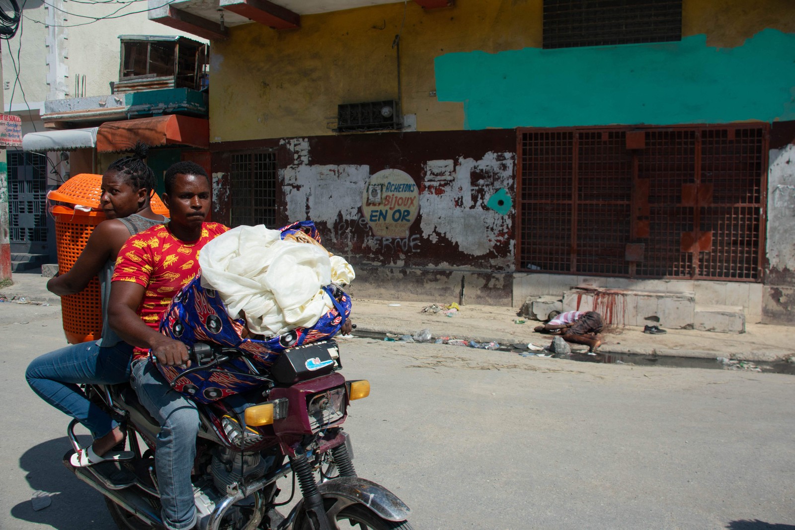 Moradores deixam suas casas enquanto a violência das gangues aumenta em Porto Príncipe, Haiti, e passam pelo corpo de uma vítima. — Foto: Clarens SIFFROY / AFP
