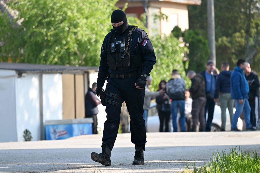 Um policial protege uma área na vila de Dubona, perto da cidade de Mladenovac, onde atirador matou várias pessoas