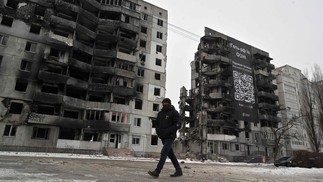 Homem passa por edifícios destruídos na pequena cidade ucraniana de Borodyanka, a cerca de 60 km da capital ucraniana, Kiev, em meio à invasão russa da Ucrânia.  — Foto: Sergei SUPINSKY / AFP