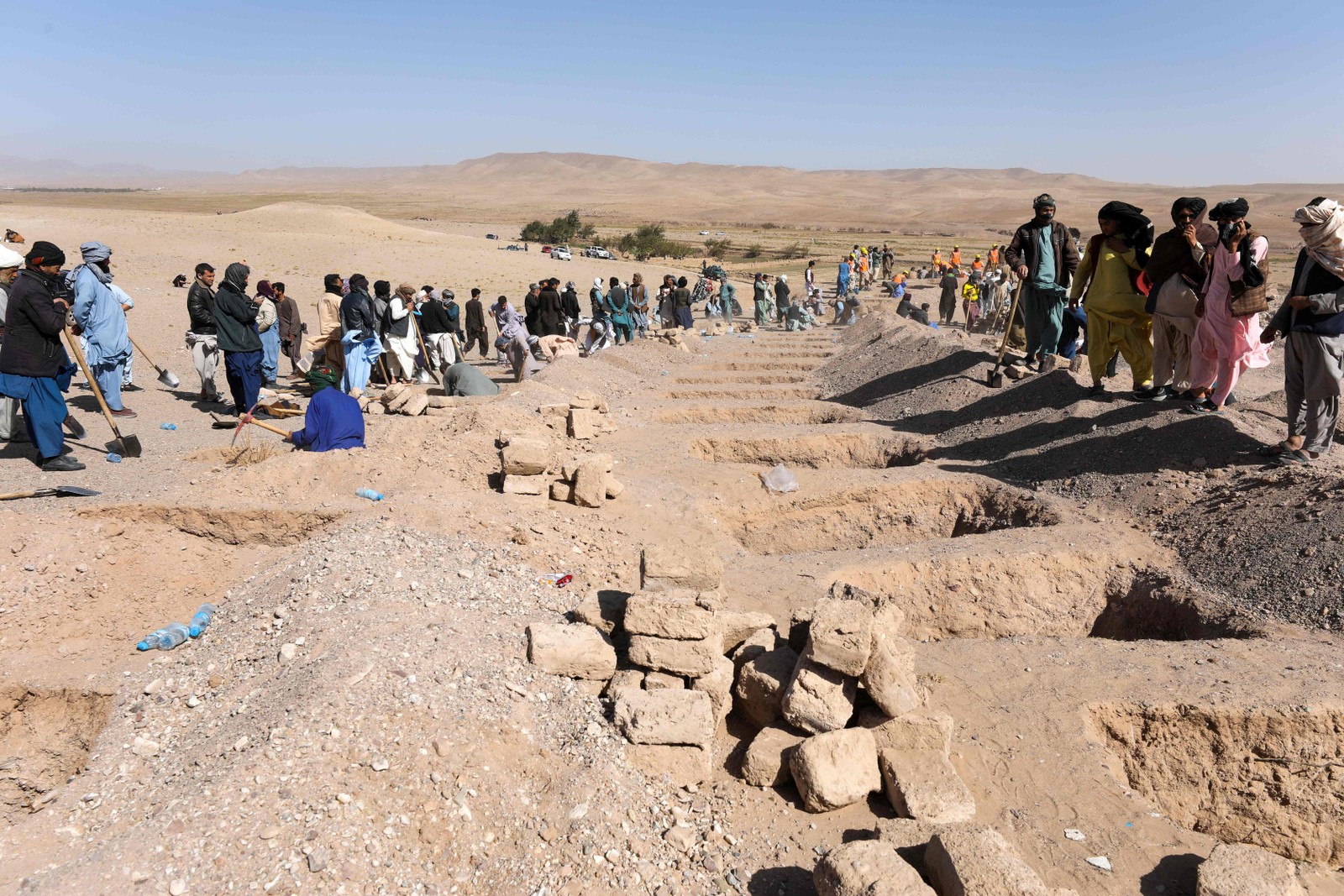 Afegãos cavam sepulturas para os corpos das vítimas dos terremotos na vila de Sarbuland, distrito de Zendeh Jan, na província de Herat, em 8 de outubro de 2023 — Foto: Mohsen KARIMI / AFP