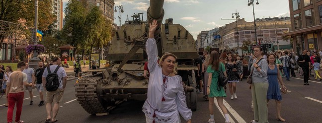Mulher usando roupas tradicionais ucranianas posa para fotos em frente a um tanque russo destruído na rua principal Khreshchatyk, no Dia da Independência da Ucrânia, em Kiev, em 24 de agosto de 2023, em meio à invasão russa da Ucrânia. — Foto: Roman Pilipey / AFP