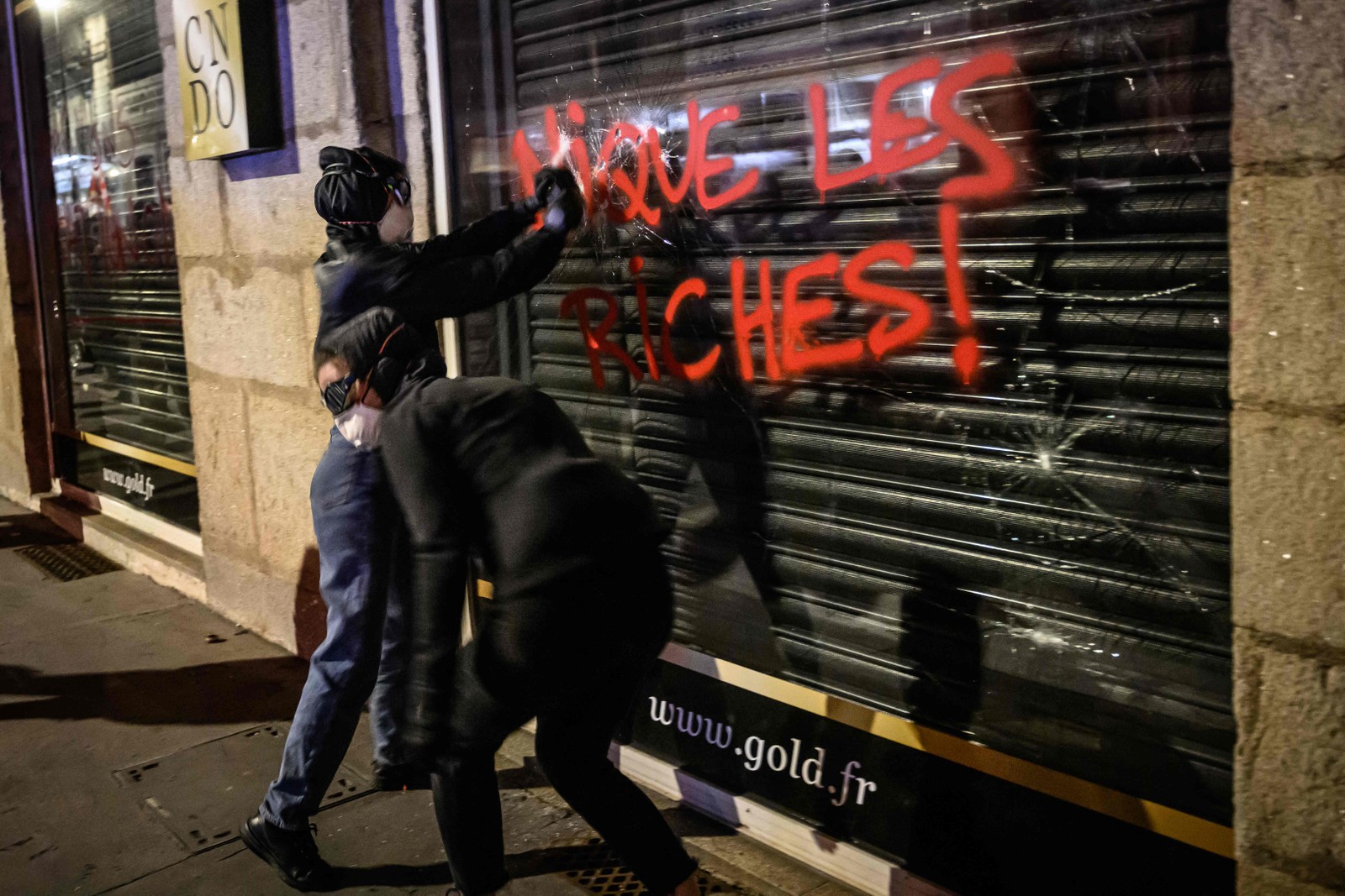 Manifestantes picham a vitrine de uma loja durante protestos contra a reforma da Previdência, em em Nantes — Foto: LOIC VENANCE / AFP