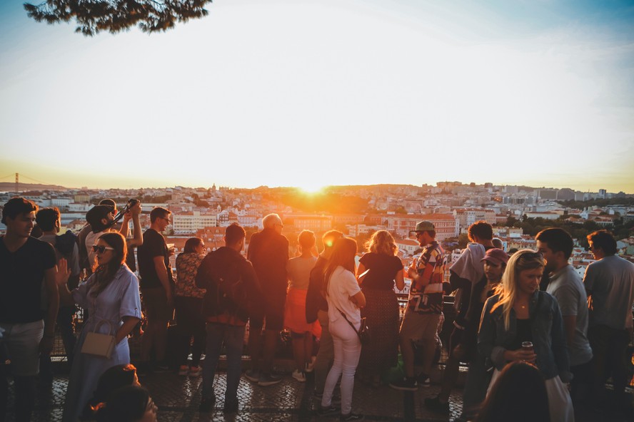 Grupo de pessoas aproveita o pôr do sol em um dos mirantes de Lisboa