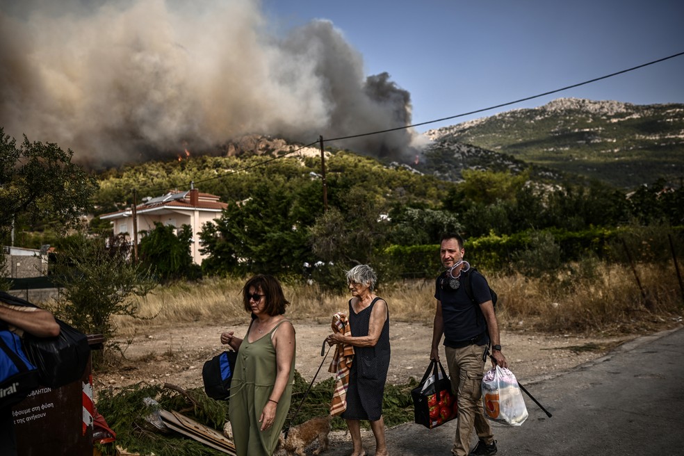 Moradores são obrigados a deixarem suas casas com o avanço dos incêndios. Muitos, no entando, se recusam — Foto: ANGELOS TZORTZINIS/AFP