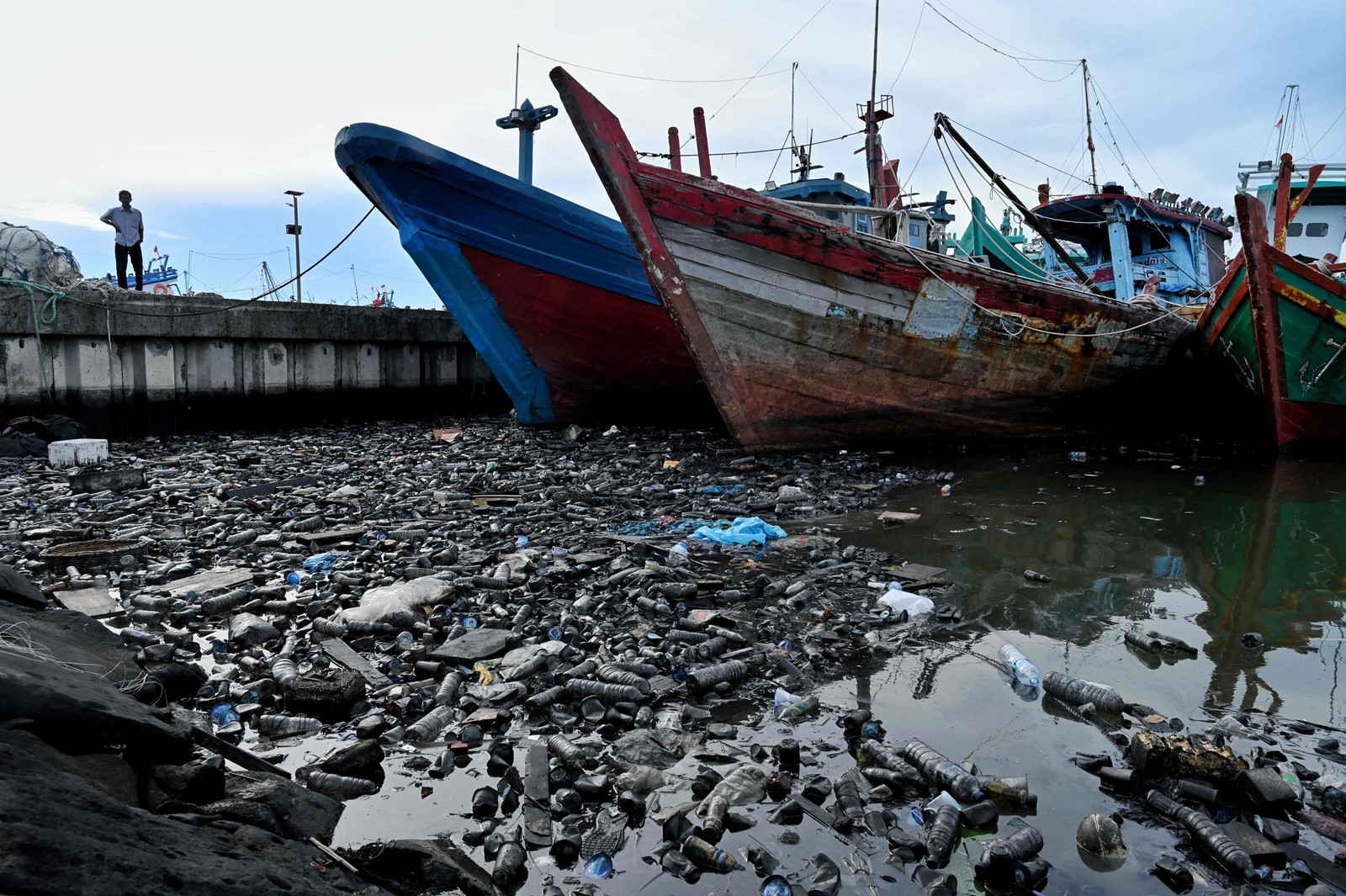 Homem observa poluição em um porto de pesca de Banda Aceh, Indonésia — Foto: CHAIDEER MAHYUDDIN / AFP