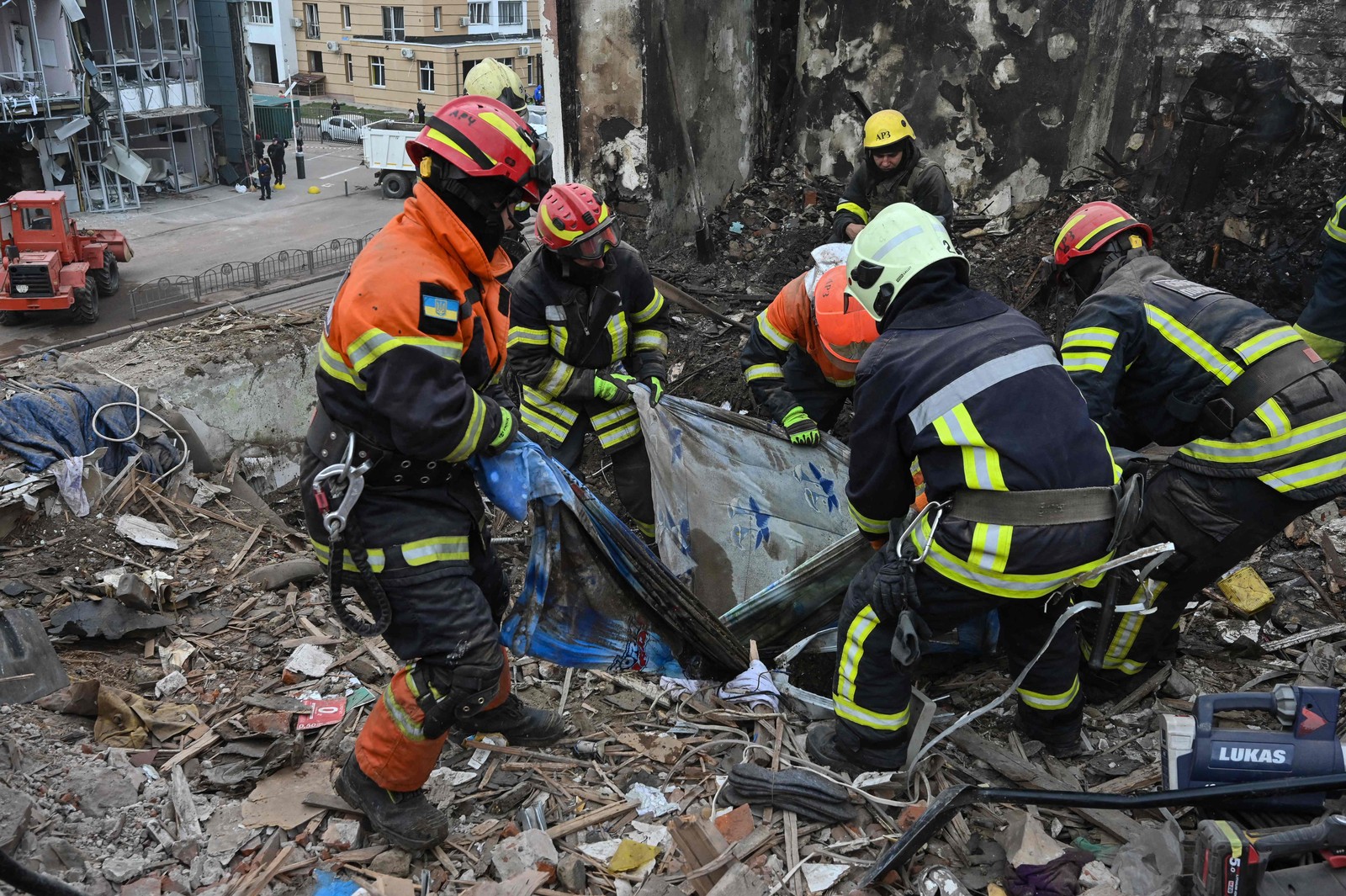 Equipes de resgate encontram um corpo entre os escombros no prédio residencial destruído após um ataque com mísseis russos em Kharkiv — Foto: SERGEY BOBOK / AFP