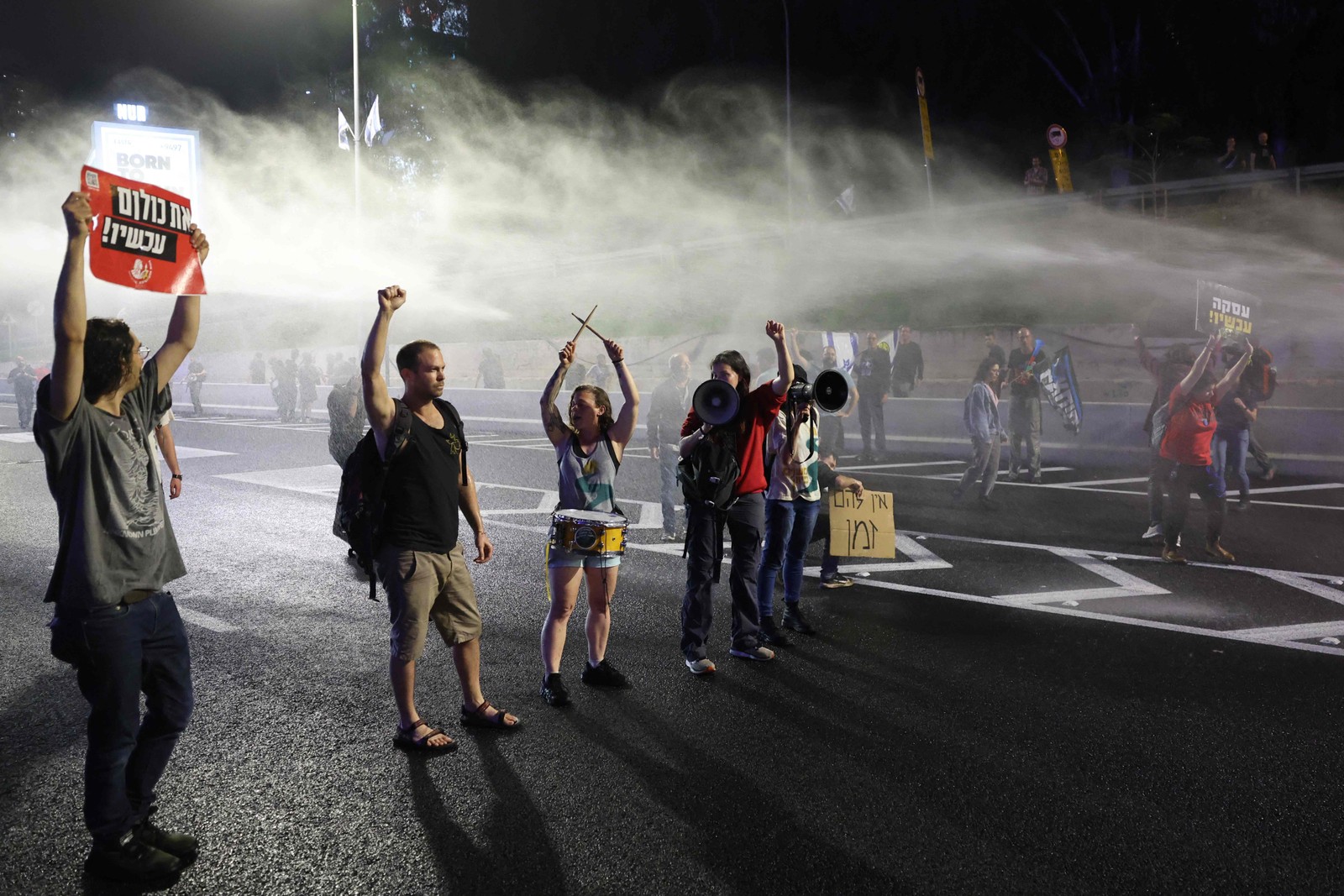 A polícia israelense lança jatos de água sobre manifestantes enquanto bloqueiam uma estrada em protesto contra o governo de Israel — Foto: JACK GUEZ / AFP