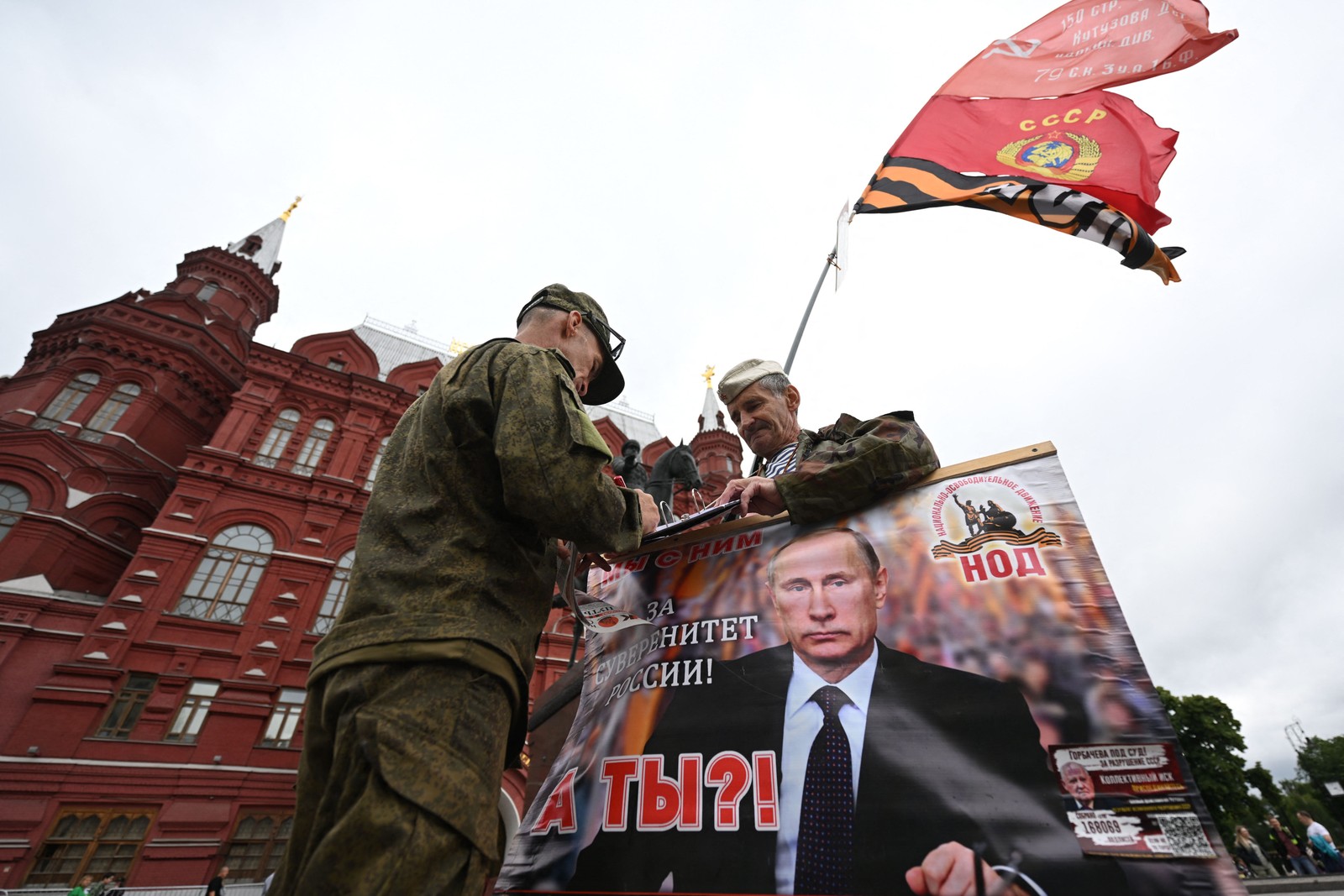 Ativista segura cartaz com imagem de Vladimir Putin na Praça Vermelha; presidente russo prometeu punir mercenários rebeldes — Foto: Natalia KOLESNIKOVA / AFP